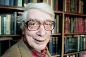 Edwin Morgan in front of a large bookcase