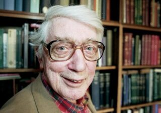 Edwin Morgan in front of a large bookcase