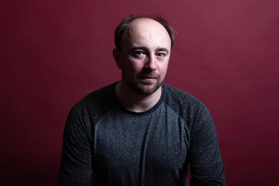 Photo of Rory Waterman wearing a blue sweatshirt, sitting in front of a purple wall.