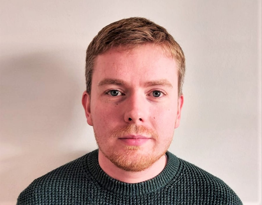James Conor Patterson with short hair and a green crew neck jumper