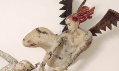 looks like a sculpture of a red haired woman with wings (angel or dragon?) holding on to the left arm of a male figure.