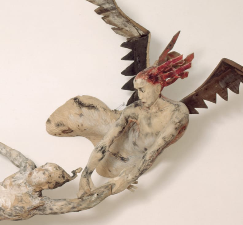 looks like a sculpture of a red haired woman with wings (angel or dragon?) holding on to the left arm of a male figure.