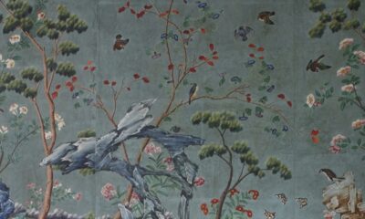 Blue Chinese wallpaper showing a watercolour design with trees and small birds. There are small flowers too.