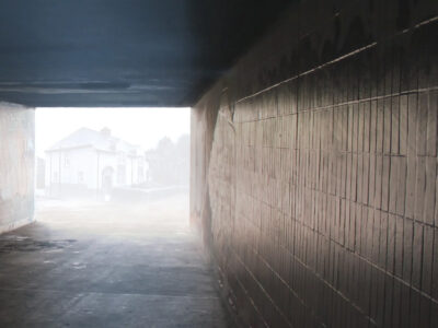 Looking through an underpass. A house can be discerned through distant mist.