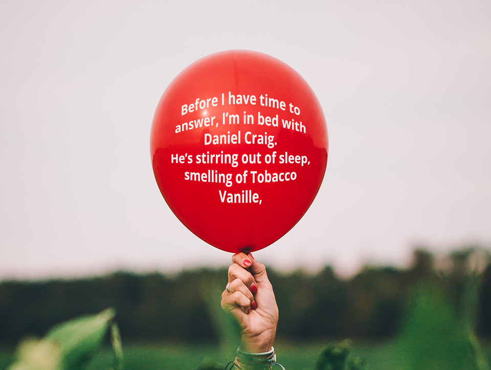 Hand holding a red balloon, written on the balloon in white text is the following "Before I have time to answer, I’m in bed with Daniel Craig. He’s stirring out of sleep, smelling of Tobacco Vanille."