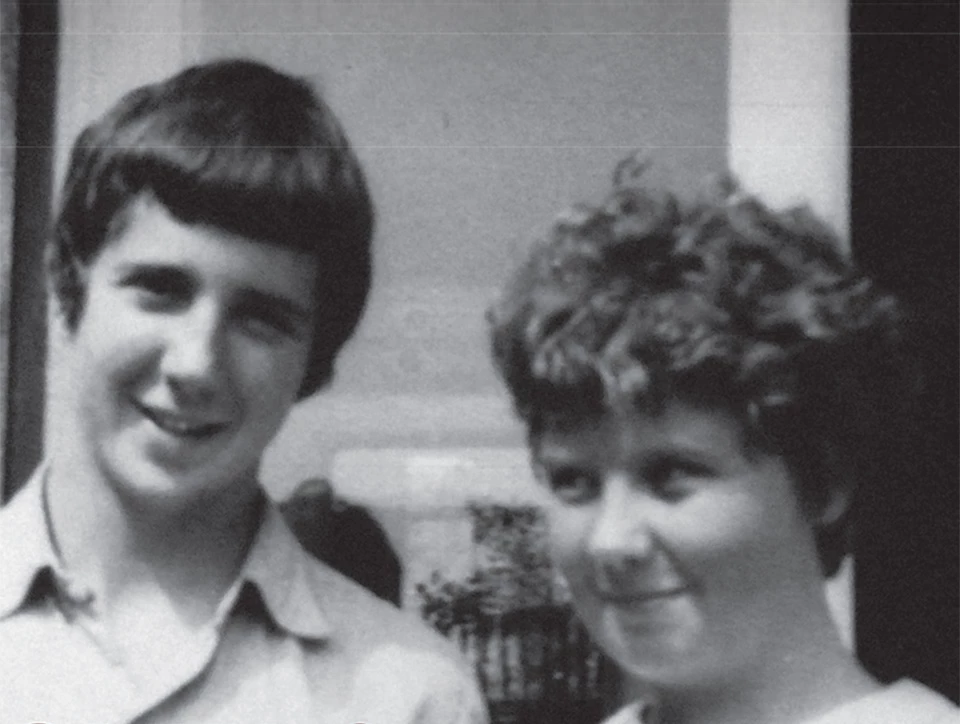 An old black and white photo of two kids, one older boy and a younger girl.
