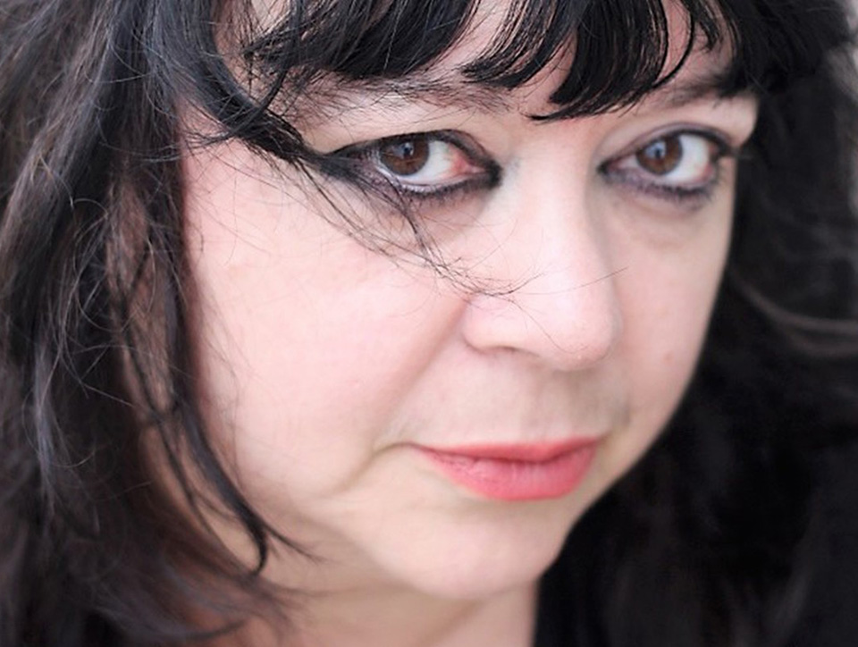 Close up photo of Diane Seuss' face. She looks intensely at the camera, heavy dark eyeshadow frames her eyes.
