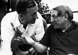 Black and white photograph of Picasso and Éluard in conversation.