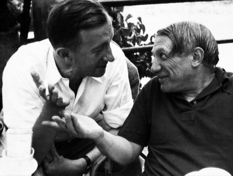 Black and white photograph of Picasso and Éluard in conversation.