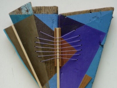 Part of book cover showing Kite form by Mike Barlow — a piece of abstract art (because we have learnt by now that nothing says competent poet more than a bit of random abstract artwork). Painted driftwood is the background to geometric shapes in shades of blue. These are criss crossed with bits of fine string. Told you ... poetry.