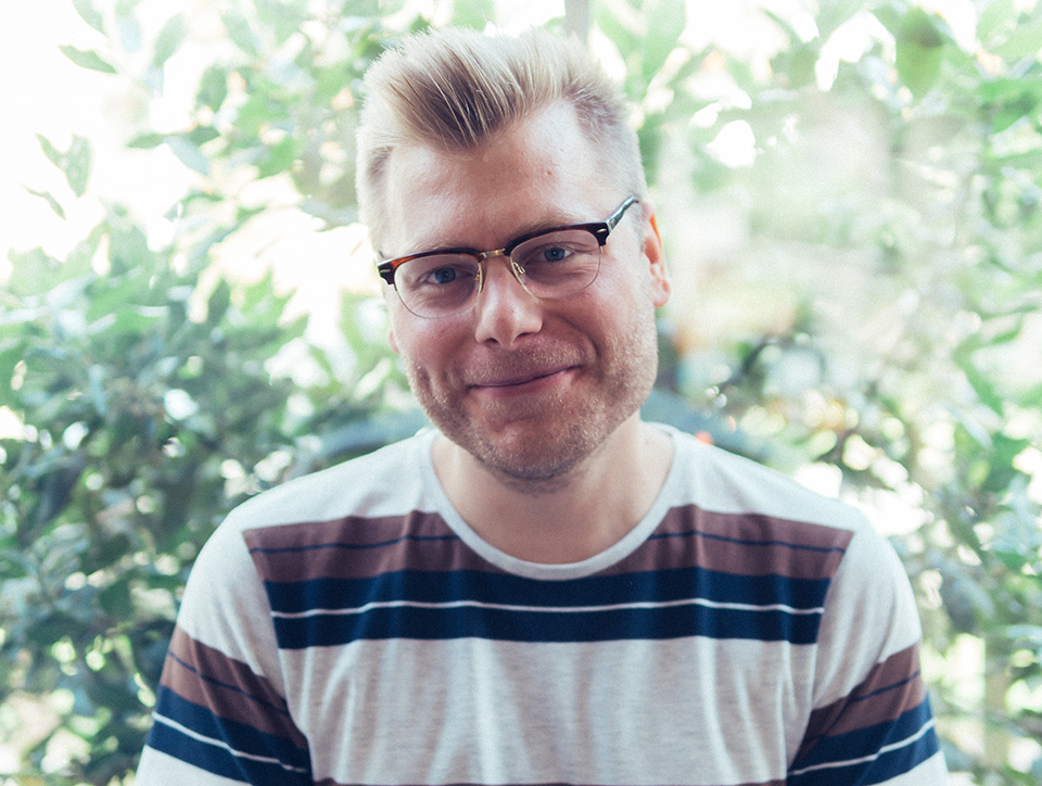 Christopher Arksey looking at the camera. He's wearing glasses and a striped top.