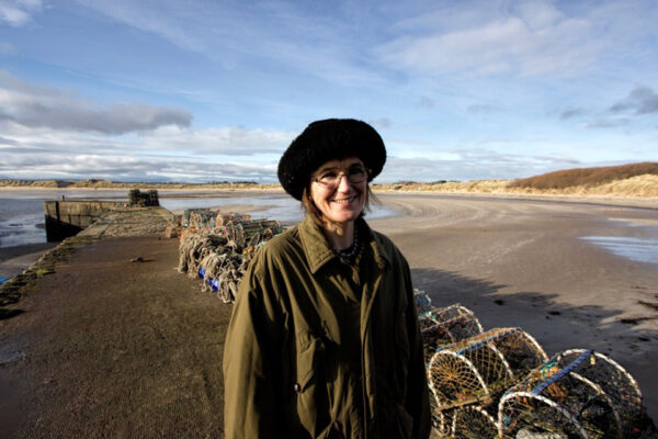 Photo of Katrina standing on the shore. Crab pots are behind her. Photo by Joe Grabham.