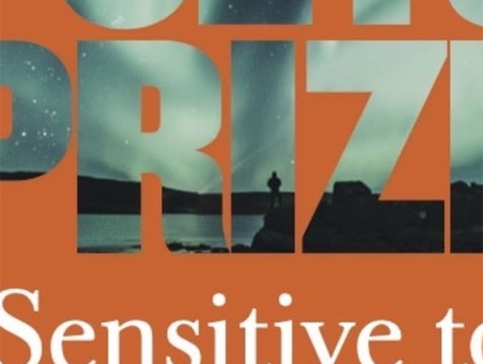 Close up of large lettering on an orange background, the lettering contains a photograph showing what looks like a shoreline.