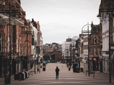 Photograph showing a streets in Leeds city center. They are empty apart from one figure in the middle of the street
