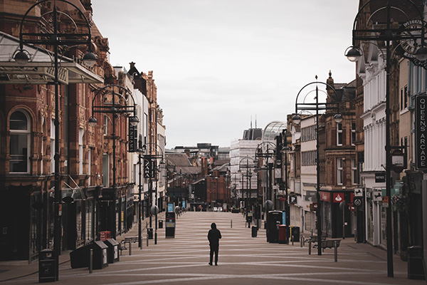 Photograph showing a streets in Leeds city center. They are empty apart from one figure in the middle of the street
