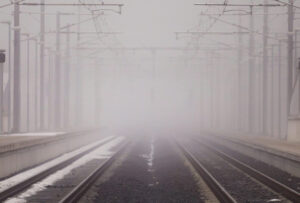 A misty photo showing train tracks disappearing to a vanishing point.