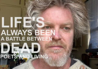 A photograph of a bearded man with wild greying hair. The words 'LIFE'S ALWAYS BEEN A BATTLE BETWEEN DEAD POETS AND LIVING' are superimposed in white text.