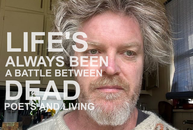 A photograph of a bearded man with wild greying hair. The words 'LIFE'S ALWAYS BEEN A BATTLE BETWEEN DEAD POETS AND LIVING' are superimposed in white text.
