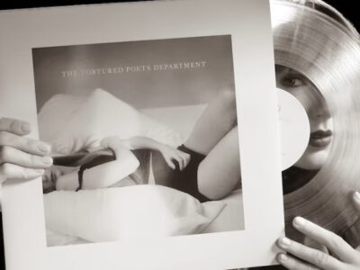A photograph of Taylor Swift taking a vinyl disc from its sleeve. the album is hers, the cover shows the normal rock'n'roll stuff, you know, woman in underwear lying on a bed etc.
