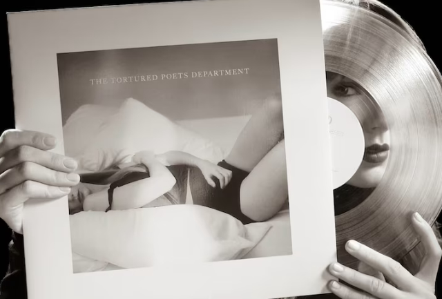 A photograph of Taylor Swift taking a vinyl disc from its sleeve. the album is hers, the cover shows the normal rock'n'roll stuff, you know, woman in underwear lying on a bed etc.