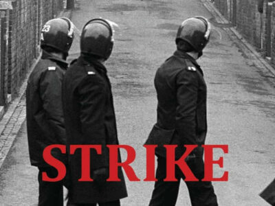 Black and white photo showing three policemen with riot helmets on a Northern backstreet.