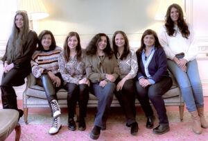 Seven women sitting on a sofa.